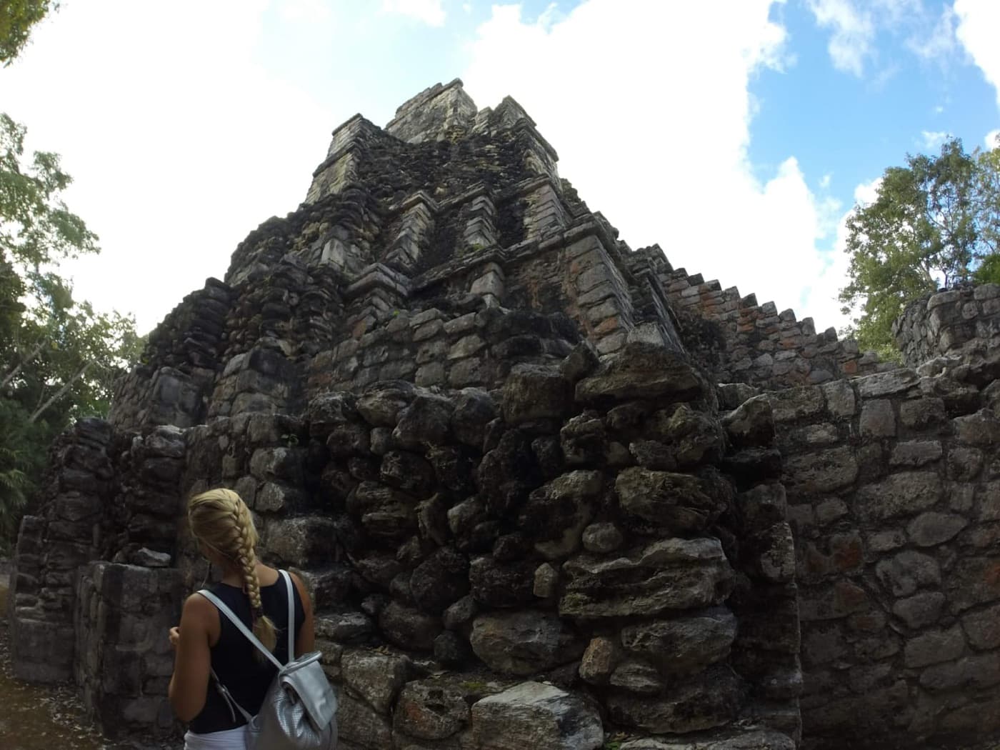 Una huésped mirando hacia un templo maya de piedra rodeado de selva